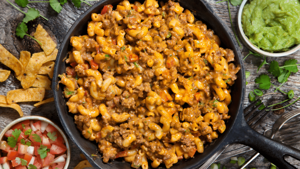 Imagem do Macarrão na panela de pressão colocado em uma frigideira junto está um pequena vasilha com vinagrete e folhas de cheiro verde