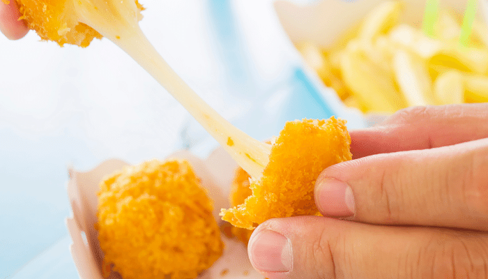 bolinho de batata com queijo pronto partido ao meio e sendo esticado pelo queijo quente.