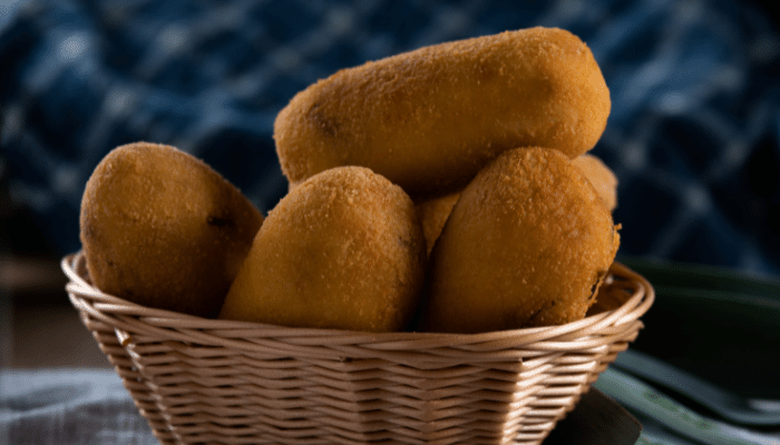 bolinho de mandioca recheado frito dentro de uma pequena cesta